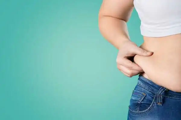 Image of woman pinching her love handles to show weight gain Merthyr Tydfil