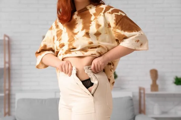 Image of woman trying to do her trousers up after pregnancy weight gain Merthyr Tydfil